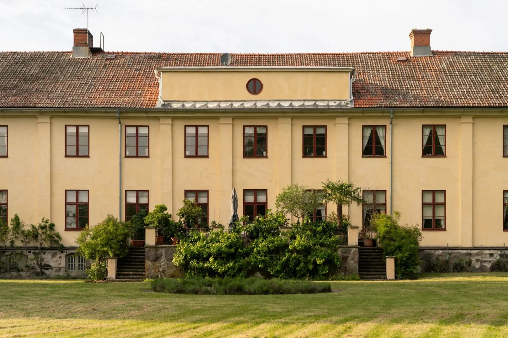 Gul herrgård med trädgård en sommardag